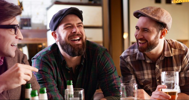 Group of three men laughing while socially enjoying beer