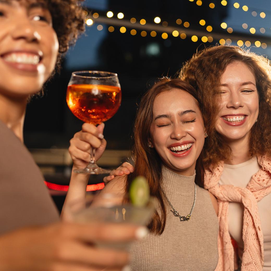Friends smiling and holding drinks at a celebration