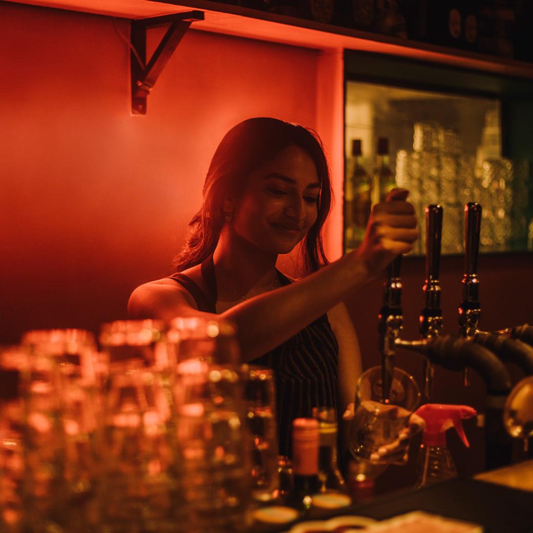 Woman serving drinks behind a bar