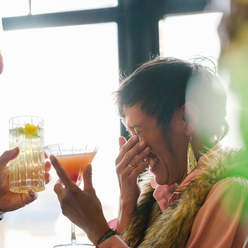 Woman laughing with a drink in hand