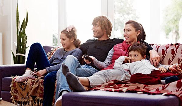 Family sitting on the couch watching tv