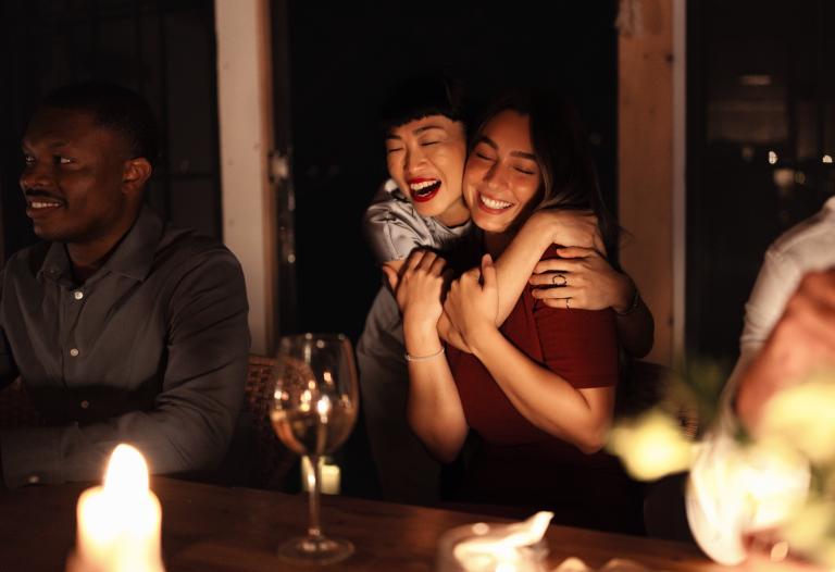 Friends hugging and enjoying drinks at a restaurant