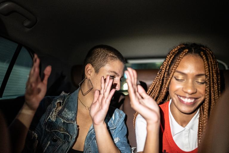 Friends dancing in the back seats of a car